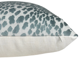 Close-up of a pillow corner with marine blue velvet spots over white fabric on the top and plain off-white textured fabric on the side, showing a small white zipper.