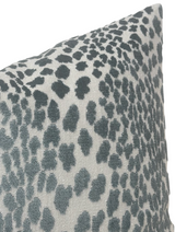 Close-up of a pillow cover featuring a spotted velvet pattern in shades of marine blue on a light grey background with a textured fabric surface.