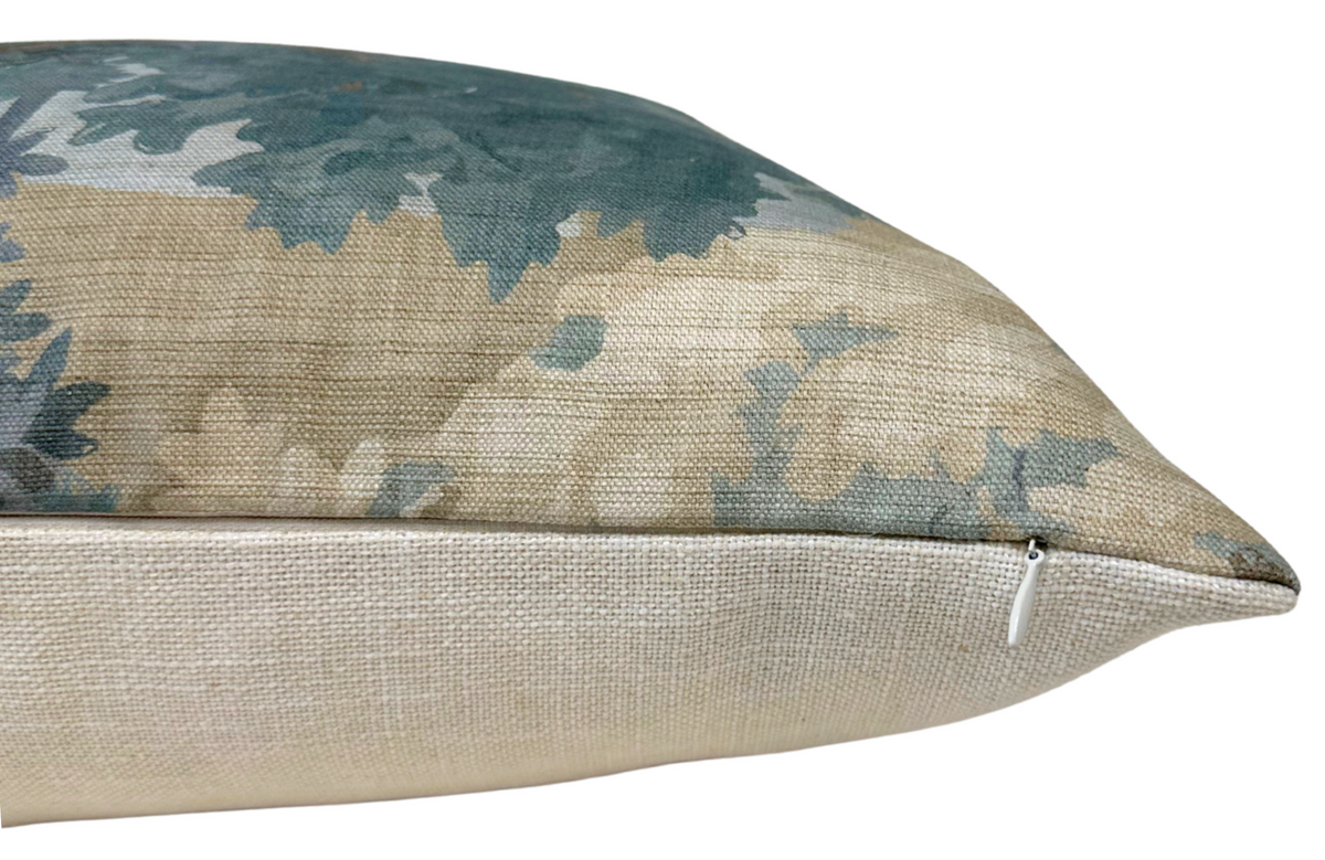 Close-up of a pillow corner showing a muted blue and beige leafy pattern on fabric with a hidden white zipper along the edge.