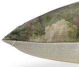 Close-up of a rectangular pillow with a textured beige fabric on the bottom and a green and brown leafy patterned fabric on top, featuring a visible zipper on the side.