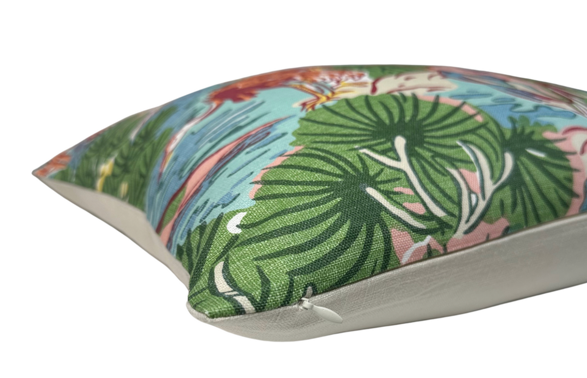 Close-up of a pillow featuring coral, green, and blue tropical leaf and flower patterns on fabric with a visible zipper along one edge