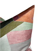 Close-up of a geometric patchwork pillow cover featuring muted rose, sage green, olive, burnt orange, and burgundy fabric sections with visible stitched seams.