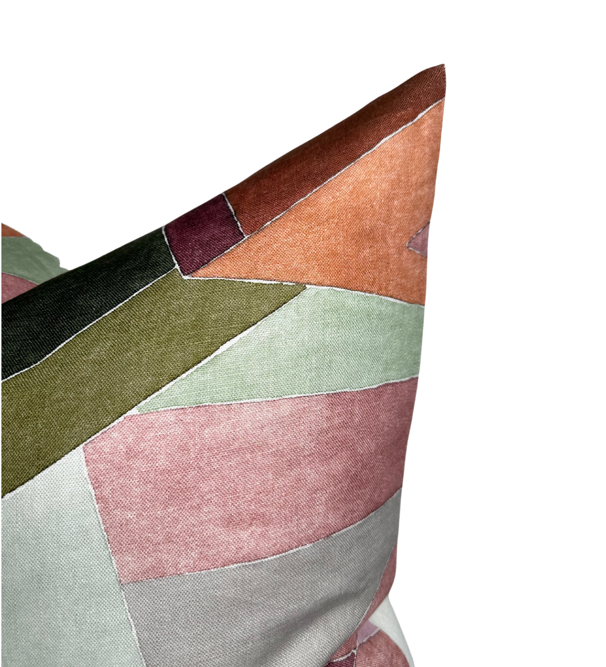 Close-up of a geometric patchwork pillow cover featuring muted rose, sage green, olive, burnt orange, and burgundy fabric sections with visible stitched seams.