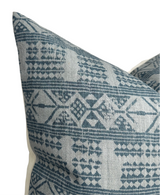 Close-up of a pillow cover featuring a mist blue geometric pattern with diamond and triangle shapes on a textured off-white fabric background.