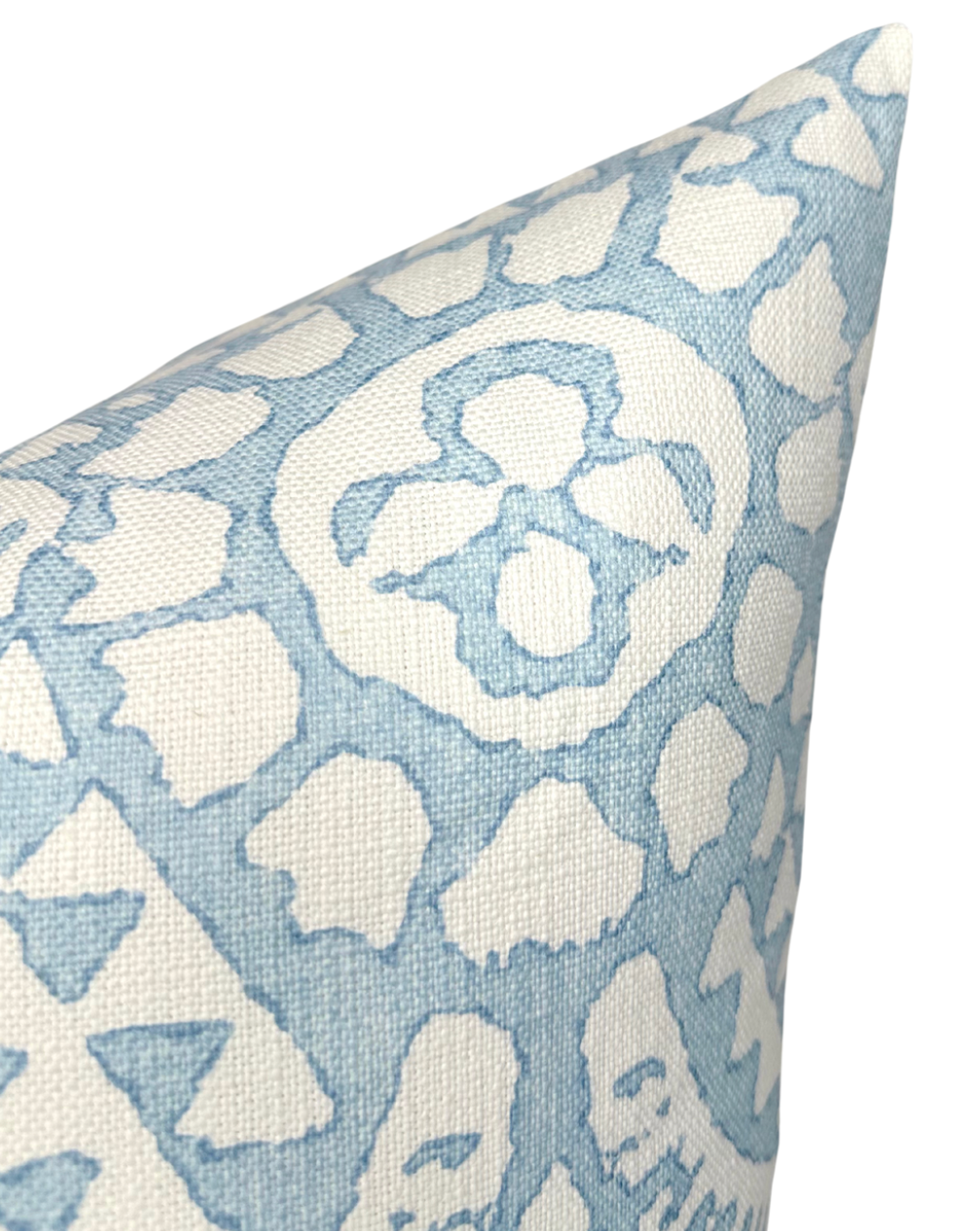 Close-up of a pillow corner with a Chamomile pattern in spa blue and white, showing textured fabric and abstract floral motifs.
