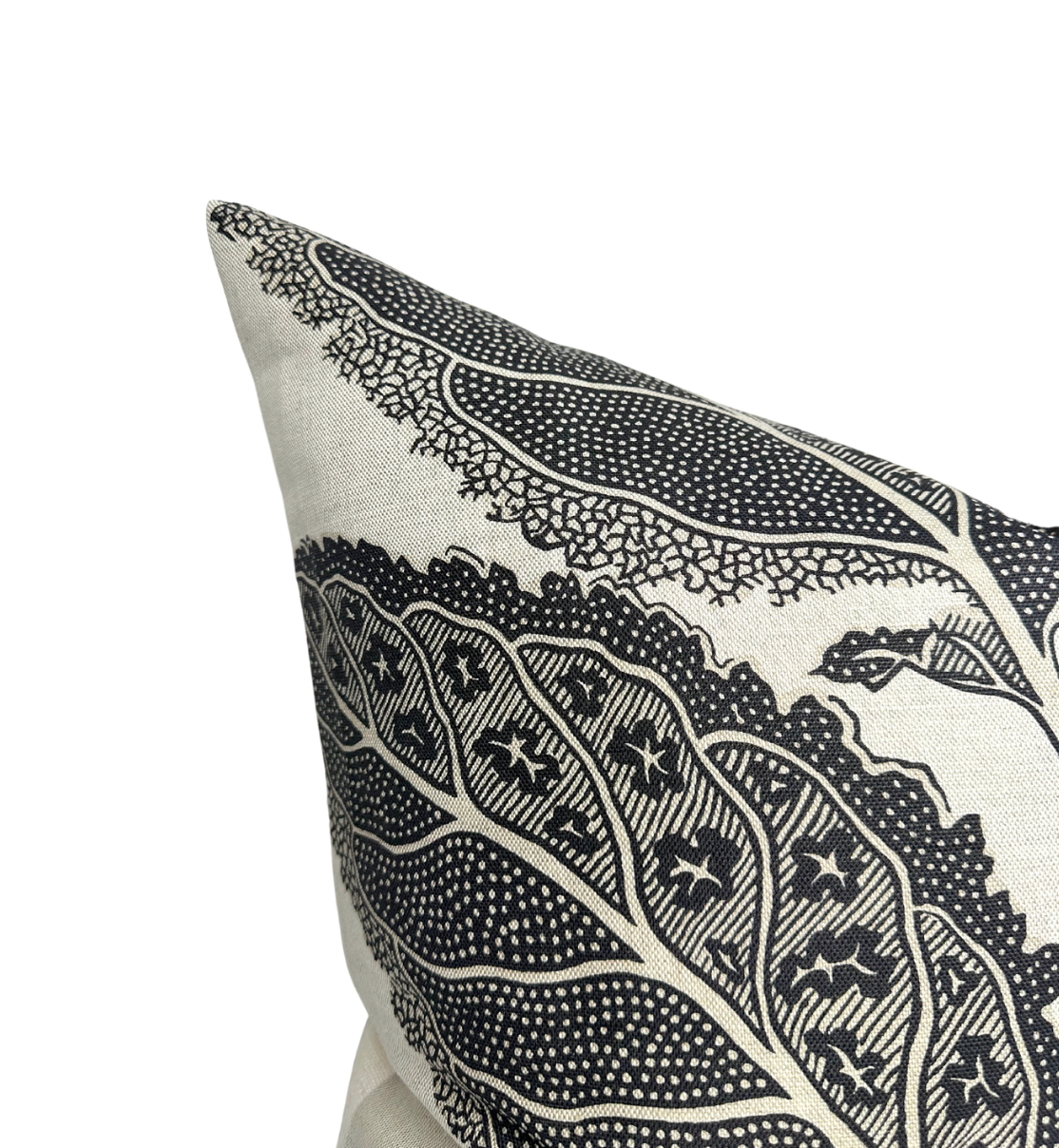 Beige pillow with large, intricate black leaf patterns featuring dotted and star-like designs on a fabric cover