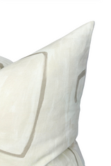 Close-up of a parchment-colored pillow cover featuring minimalist, hand-drawn taupe graffito line patterns on a textured fabric surface.