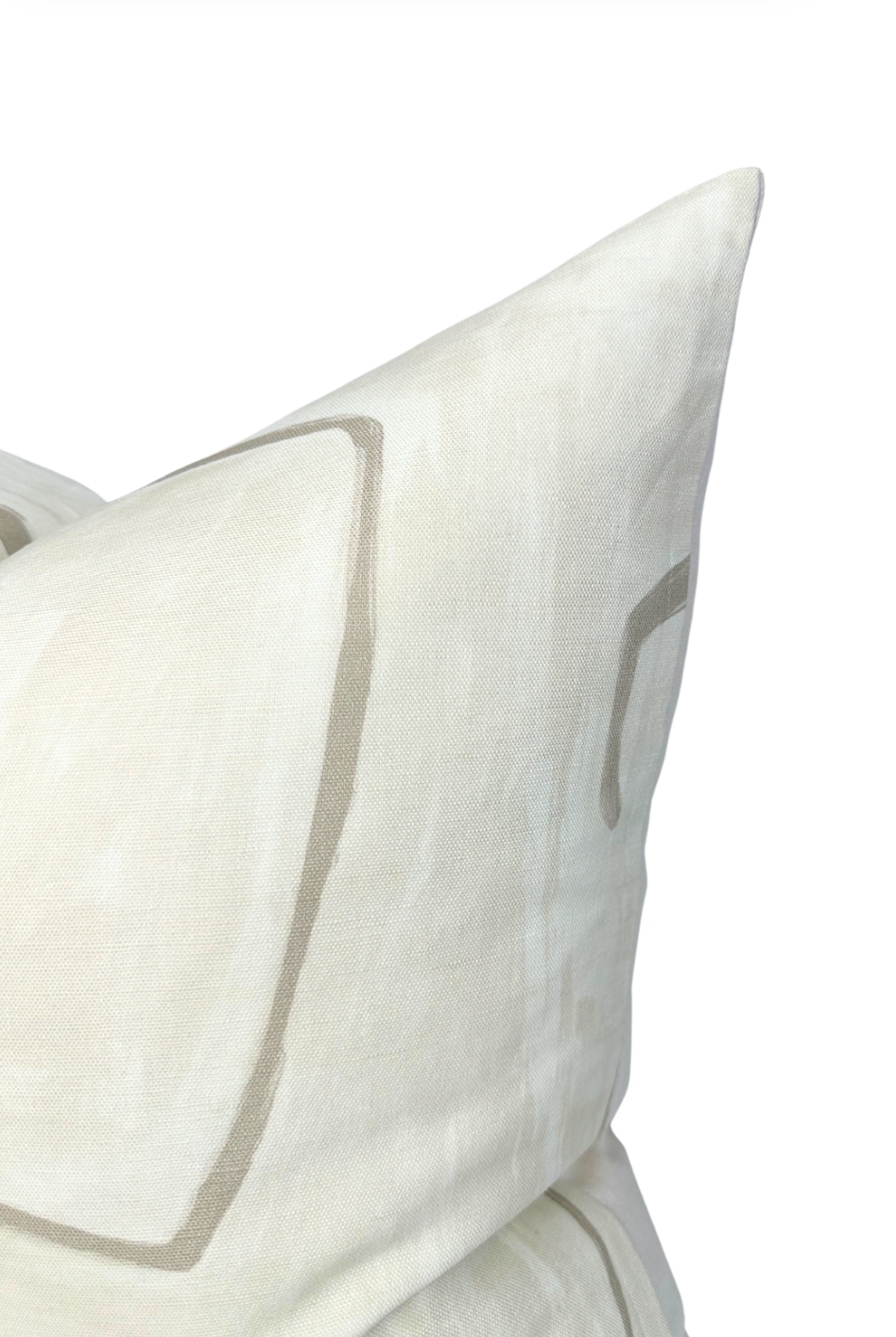 Close-up of a parchment-colored pillow cover featuring minimalist, hand-drawn taupe graffito line patterns on a textured fabric surface.