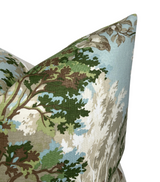Corner of a fabric pillow cover featuring a detailed toile pattern with green and brown tree branches and white foliage on a light blue background.