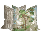 Two square pillows, one with green and blue toile print featuring trees and foliage, the other with a simple beige and white geometric pattern.