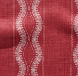 Red fabric with vertical white wavy lines and small dot patterns, showing a textured woven surface and subtle vertical stitch details.