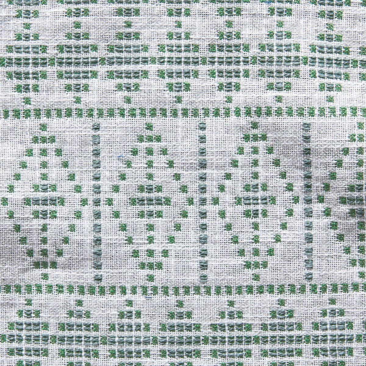 Light-colored woven fabric with green geometric diamond and rectangular patterns creating a textured, tribal-inspired design.