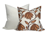 Two square decorative pillows, one with a textured cream fabric and the other with an ochre floral pattern on a cream background.