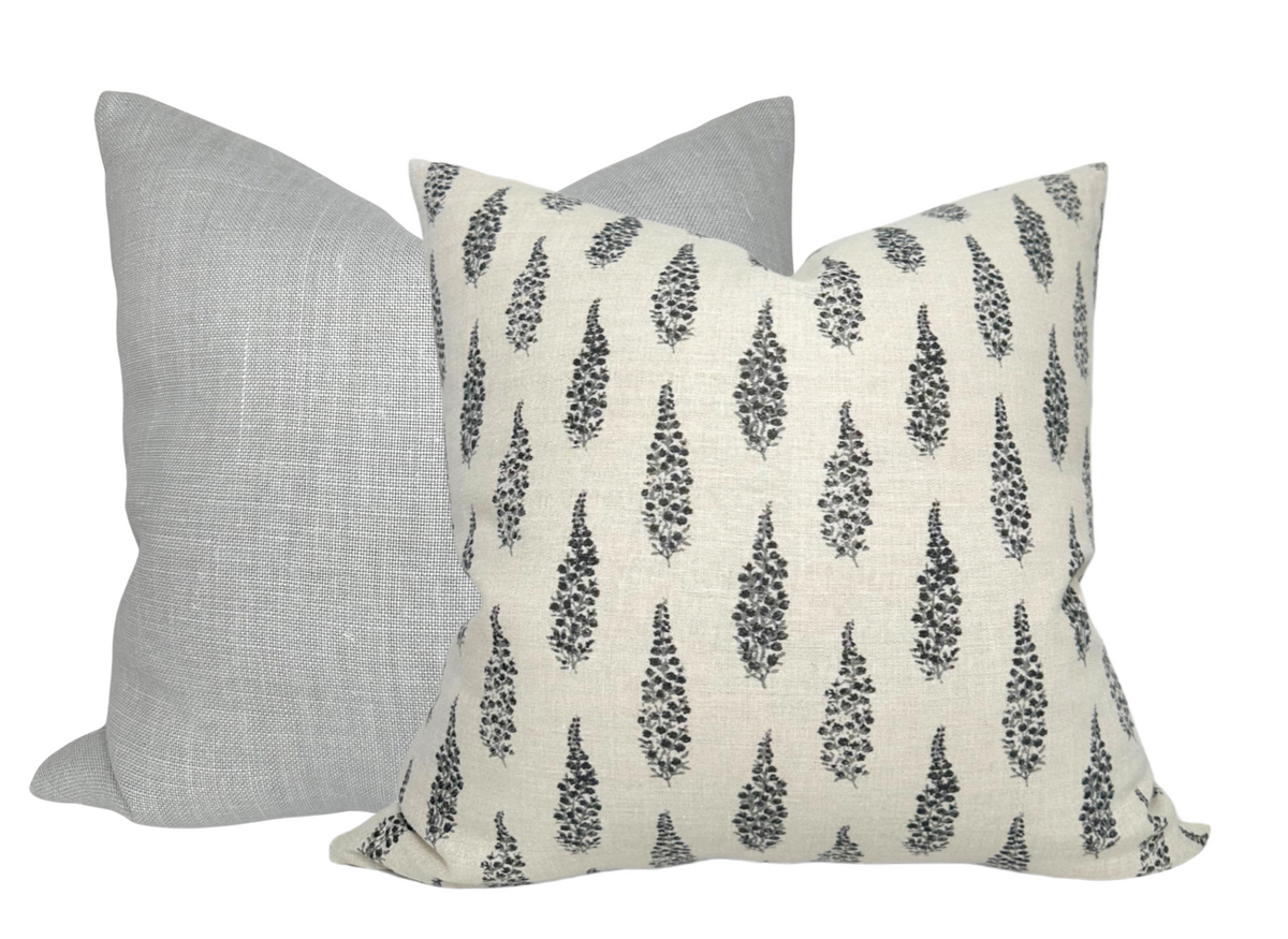 Two square linen pillow covers, one in solid light gray and the other in cream with a black abstract leaf pattern, shown side by side.