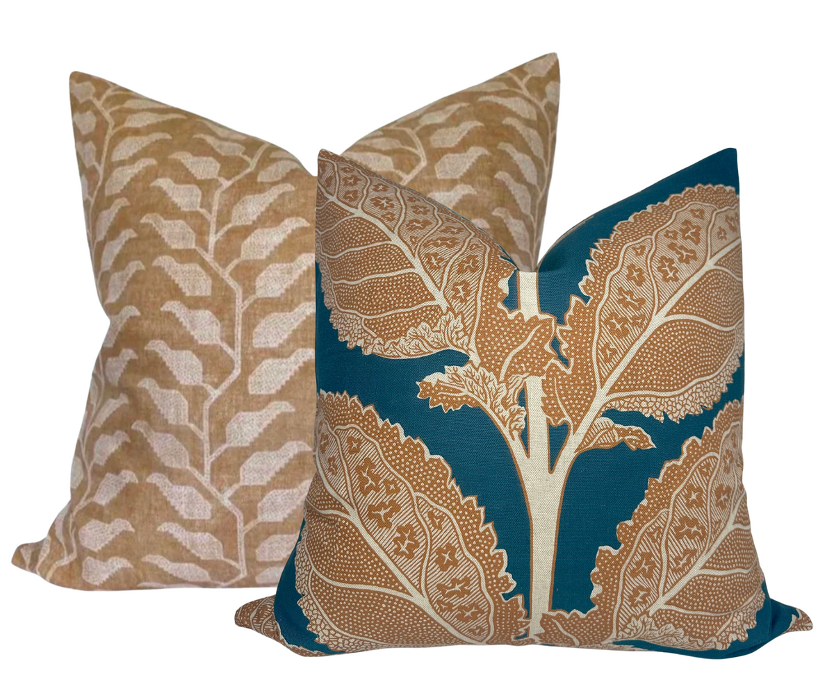 Two decorative pillows with botanical patterns, one in ochre with a white abstract leaf design and the other in mineral blue featuring a large detailed brown leaf motif.