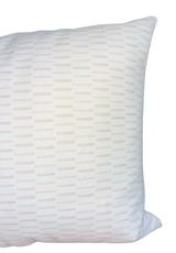Pillow cover with a subtle geometric pattern of horizontal dashes in soft pastel shades on a white background, shown at an angle highlighting its texture and shape.