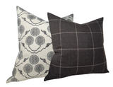 Two decorative pillows with Susan Connor Textiles designs: one with a gray and white circular botanical print, the other dark gray with a light grid pattern.