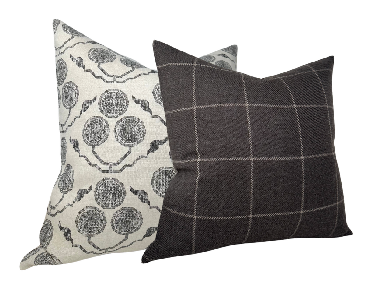 Two decorative pillows with Susan Connor Textiles designs: one with a gray and white circular botanical print, the other dark gray with a light grid pattern.