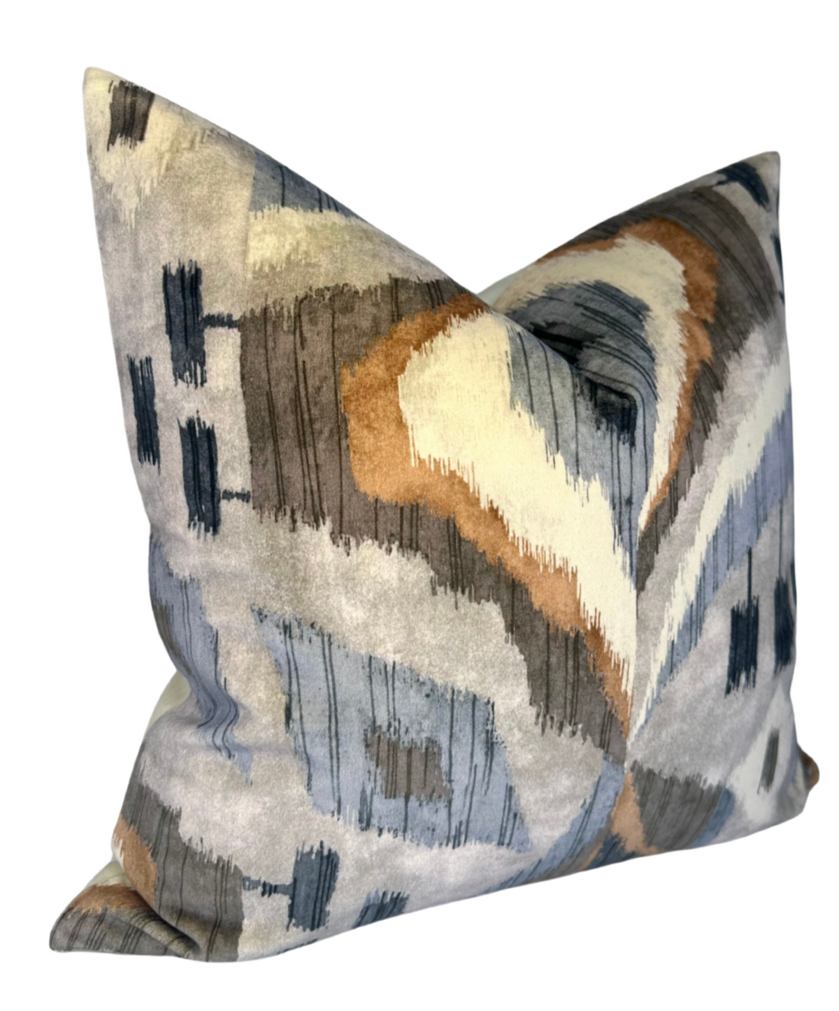 Square pillow with abstract pattern in blue, beige, brown, and gray hues, featuring irregular brushstroke-like shapes and soft velvet texture.