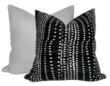 Two square pillows with knife edges, one in solid light gray linen fabric and the other in black fabric patterned with white irregular horizontal and vertical lines forming a modern geometric design.
