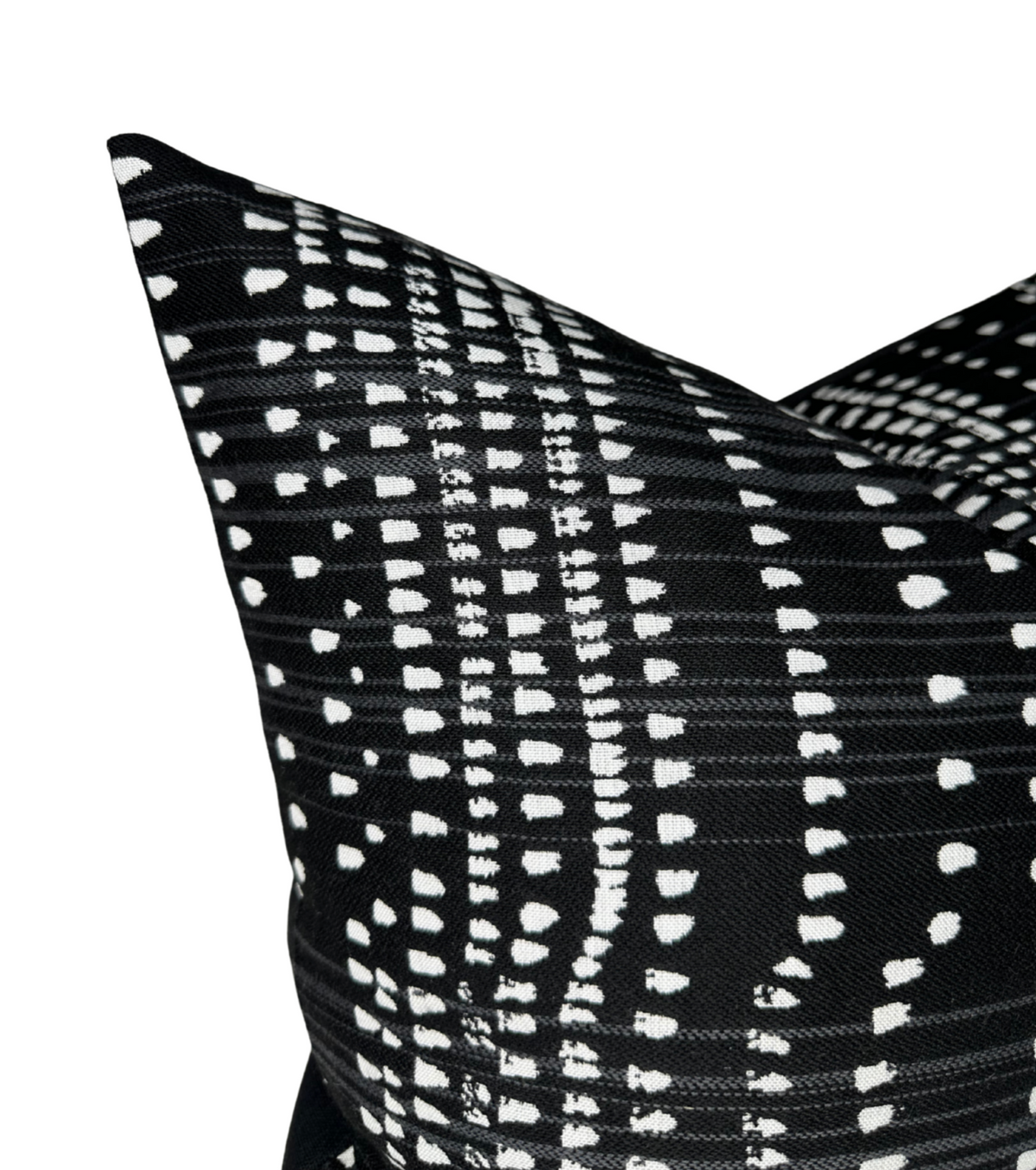 Close-up of a black pillow cover with white irregular dotted and dashed vertical lines creating a linear pattern, showing textured fabric and sharp corner details.