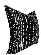 Square black pillow with a linear white dashes pattern creating horizontal and vertical grid lines, displayed at a slight angle.