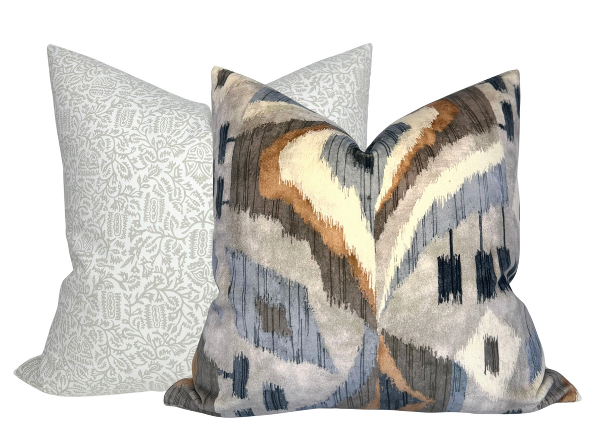 Two decorative pillow covers, one with a subtle taupe floral pattern on a light background, the other with a bold abstract pattern in taupe, gray, and rust tones.