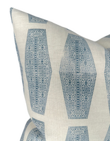 Close-up of an off-white pillow cover with light blue intricate geometric and floral inlay patterns arranged in elongated hexagonal shapes, showing fabric texture and corner detail.