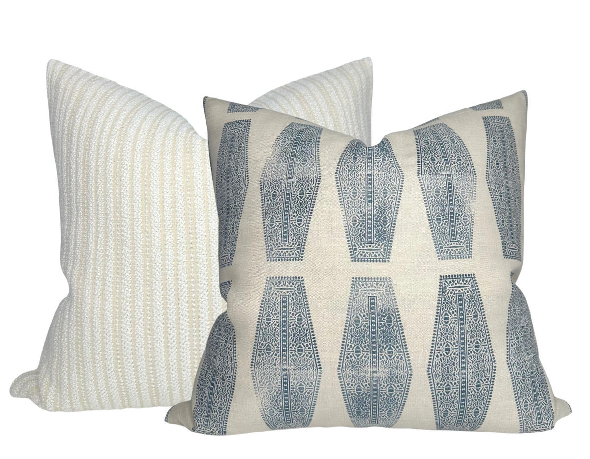 Two textile pillow covers, one with vertical beige and white stripes and the other with blue geometric inlay pattern on a natural background, arranged overlapping.
