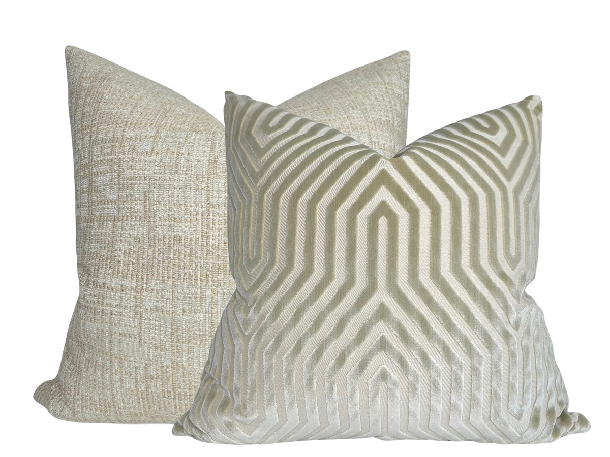 Two square pillows with textured fabric; front pillow features a geometric maze pattern in shades of greige, while the back pillow has a subtle woven texture in a soft neutral tone.