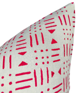 Close-up of a light beige pillow cover with a repeating geometric pattern of red vertical lines, dots, and triangles.