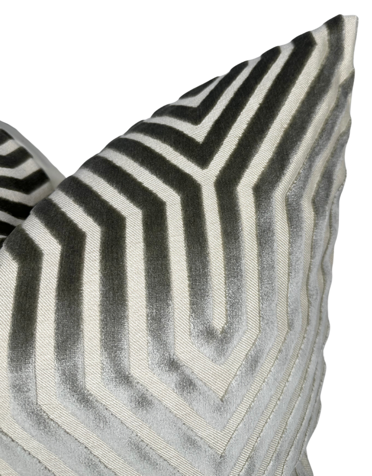 Close-up of a pillow cover featuring a geometric chevron pattern in shades of dove grey and cream with a velvet texture.