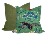 Square pillow with textured jade green fabric behind a rectangular pillow featuring a colorful bird and floral pattern on a jade green background.