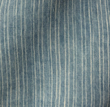 Close-up of fabric with vertical off-white pinstripes on a soft, washed aurora blue background, showing subtle texture and light natural creases.