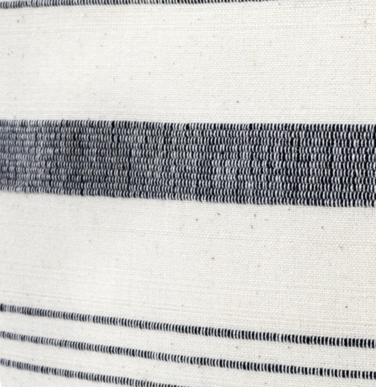 Close-up of a woven textile pillow cover featuring a wide dark gray stripe and two sets of finer parallel dark gray lines on a natural off-white background.