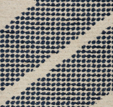 Close-up of woven off-white fabric with diagonal rows of clustered indigo blue dots forming a textured geometric pattern.