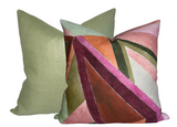 Two square pillows, one solid muted green and the other with abstract geometric pattern in rose, burgundy, olive, and blush tones with velvet texture.