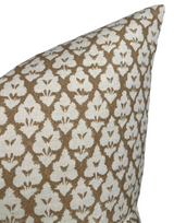 Close-up of a brown and cream pillow cover with a repeating abstract floral pattern and a textured fabric surface.