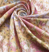 Swirled floral-patterned linen fabric in blush tones featuring soft pink, lavender, cream, and muted green hues with delicate flower and leaf designs.