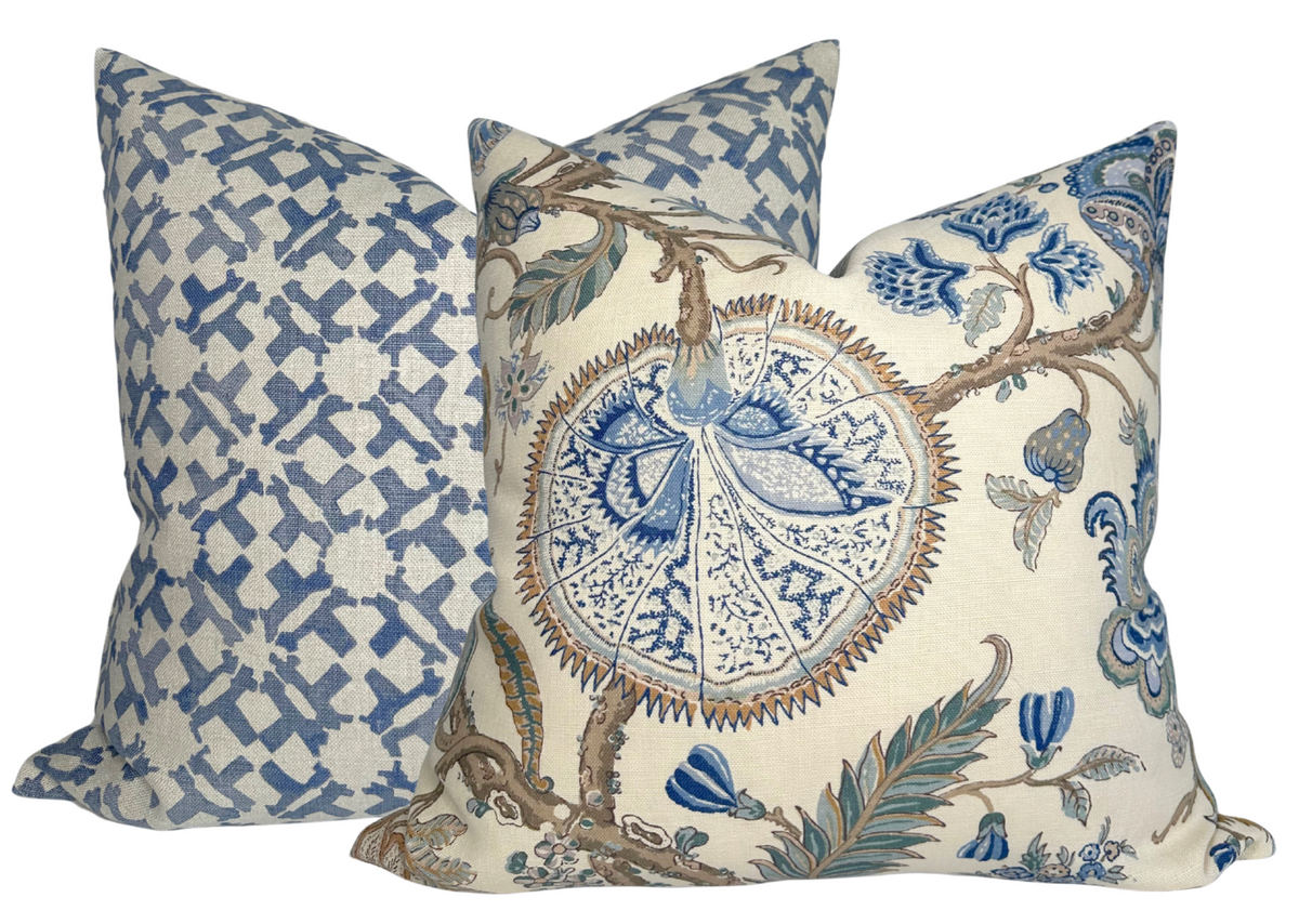 Two decorative pillow covers with blue and cream patterns, one with geometric indigo blue shapes and the other with floral branches and starburst motifs.