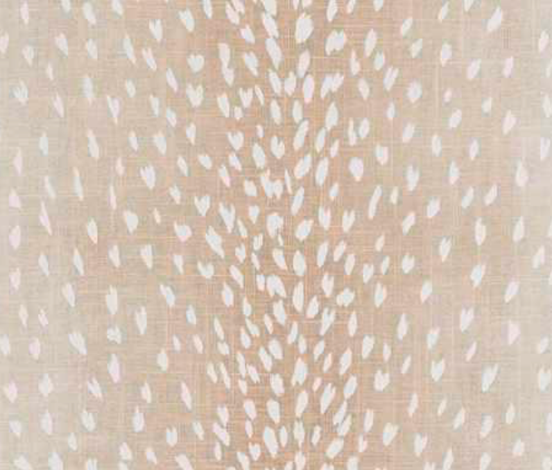 Close-up of a fabric with a beige background and scattered white and light pink antelope-inspired spots arranged in vertical pattern.