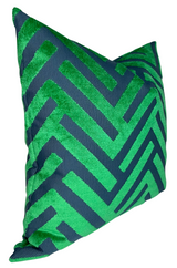 Square pillow cover with a geometric zigzag pattern in emerald green cut velvet on a dark blue fabric background, shown at an angle.