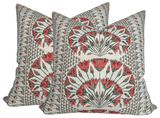 Two square pillow covers with coral and black floral patterns arranged in fan shapes on a beige background with geometric border designs.