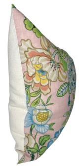 Square pillow with blush background featuring colorful peony floral patterns in green, blue, yellow, and white, paired with a plain off-white fabric on the side.