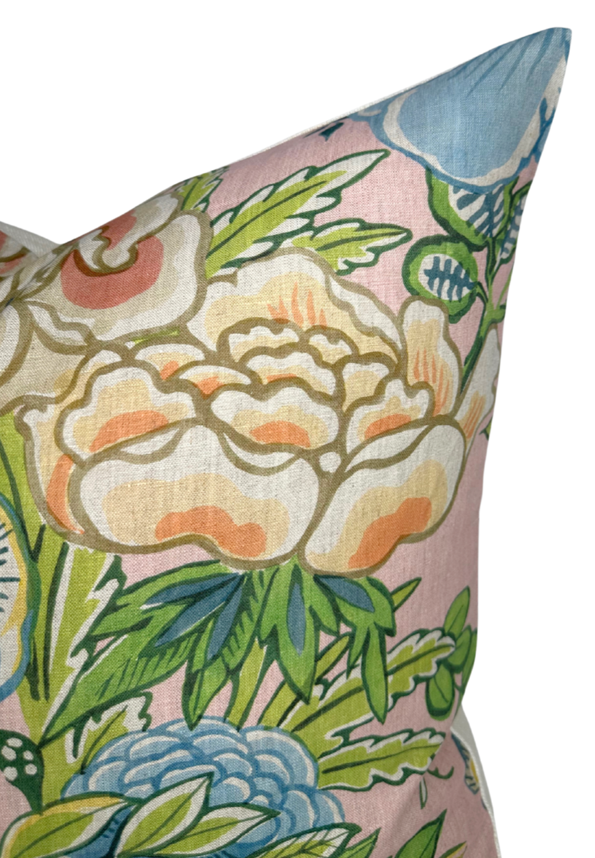 Close-up of a blush pink pillow cover featuring a large cream and peach peony with green leaves and blue floral accents in a painterly style.