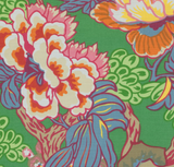 Close-up of a pillow cover fabric with large, stylized floral patterns in pink, orange, purple, and green on a green background.