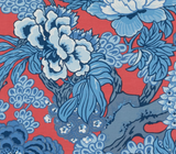 Red fabric background with detailed blue and white floral and leafy pattern featuring large blossoms and intricate branches.