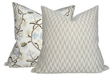 Two pillows, one with tan and white woven geometric pattern, the other with cream fabric featuring brown and blue botanical branch design, side by side.