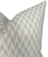 Close-up of a tan brown woven pillow cover with a repeating chevron pattern in neutral tones and a textured fabric surface.