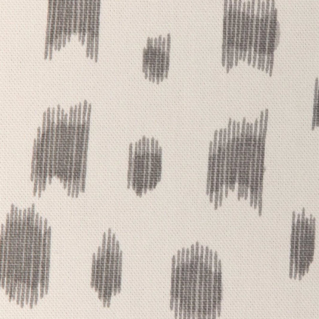 Close-up of Les Touches pillow cover fabric showing irregular gray brushstroke dots on an off-white textured background.